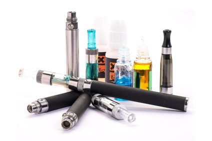 Group of electronic cigarette nicotine inhalator ,bottles with liquids behind the inhalator. isolated on white background
